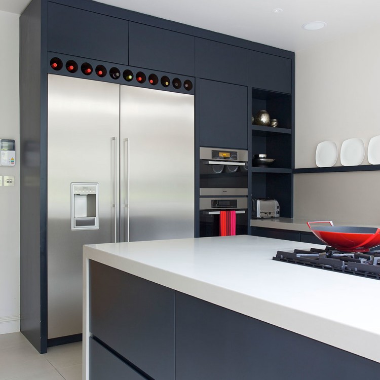 Dark kitchen design with stainless double wall oven next to stainless refrigerator