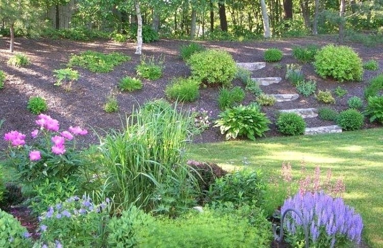 A retaining wall is great for a hillside flower bed because it creates planting opportunities when you select construction materials that allow you to plant